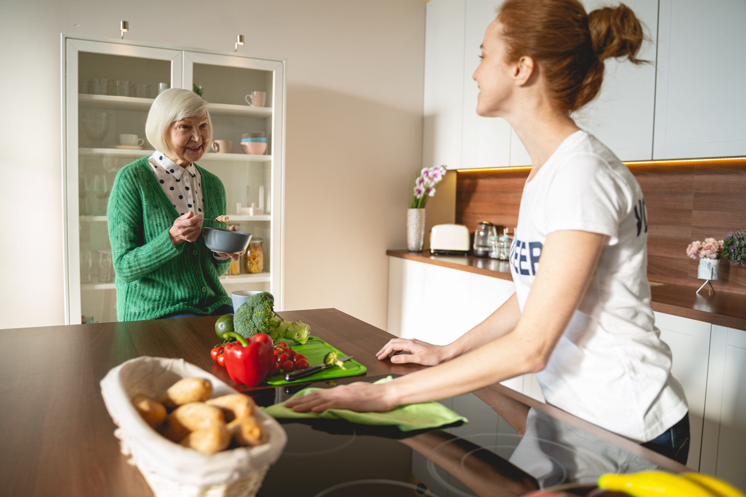 Delighted young volunteer cleaning kitchen for pensioner