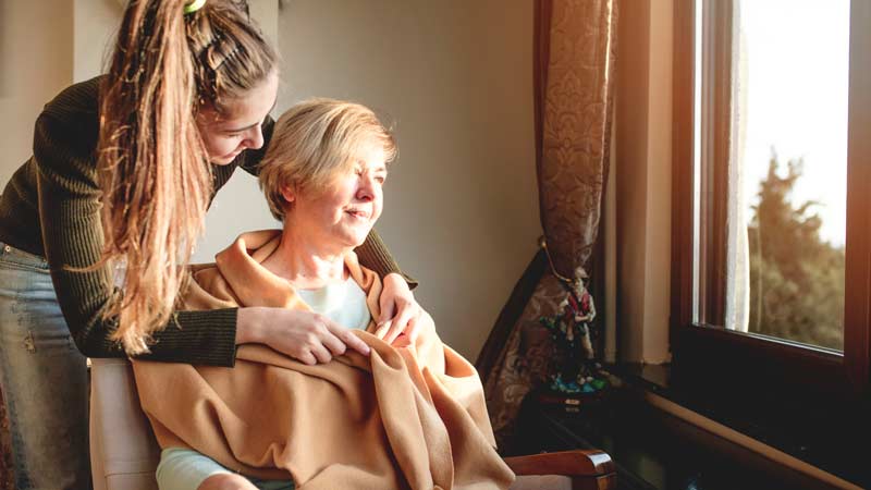 Home health care aide taking care of woman in chair